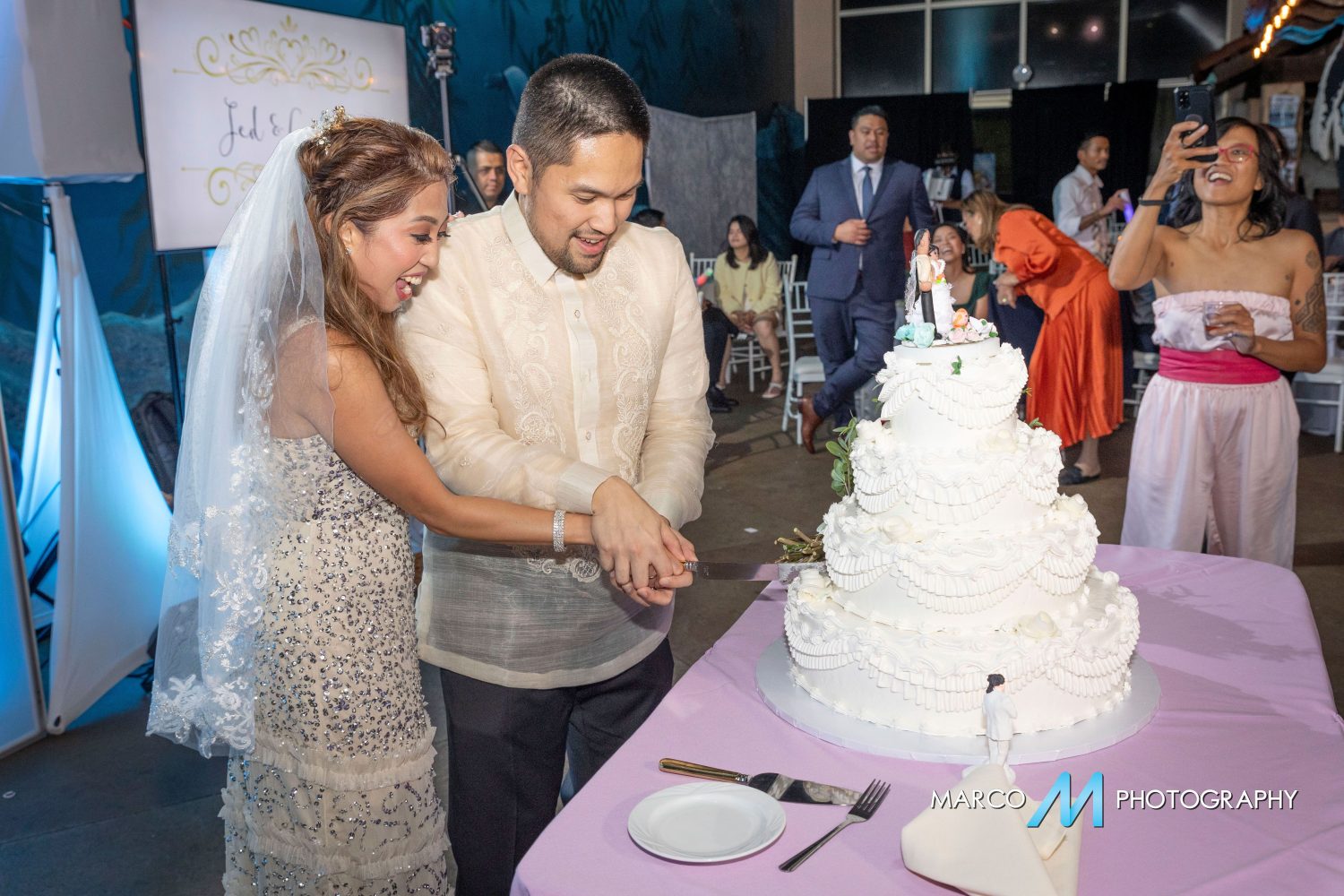Bride and groom cutting wedding cake in front of guests