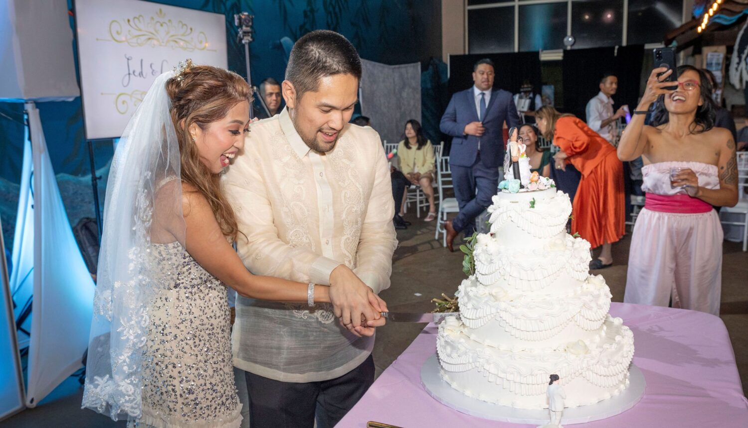 Bride and groom cutting wedding cake in front of guests