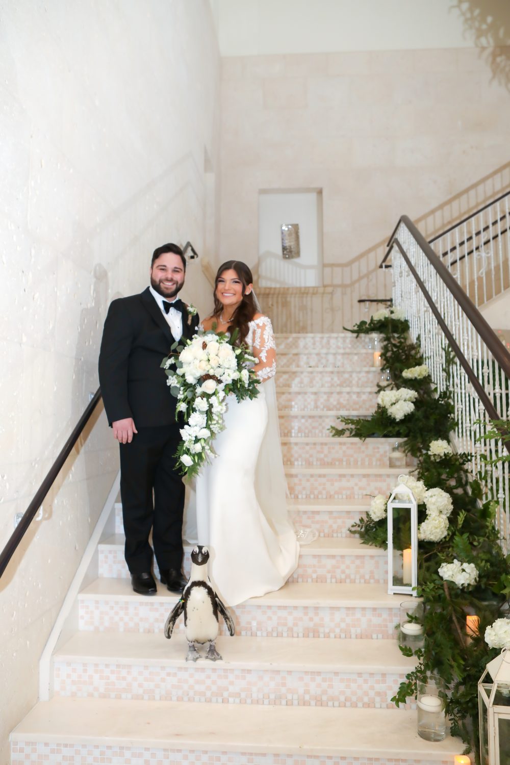 Bride and Groom on stairs with penguin, lanterns and florals