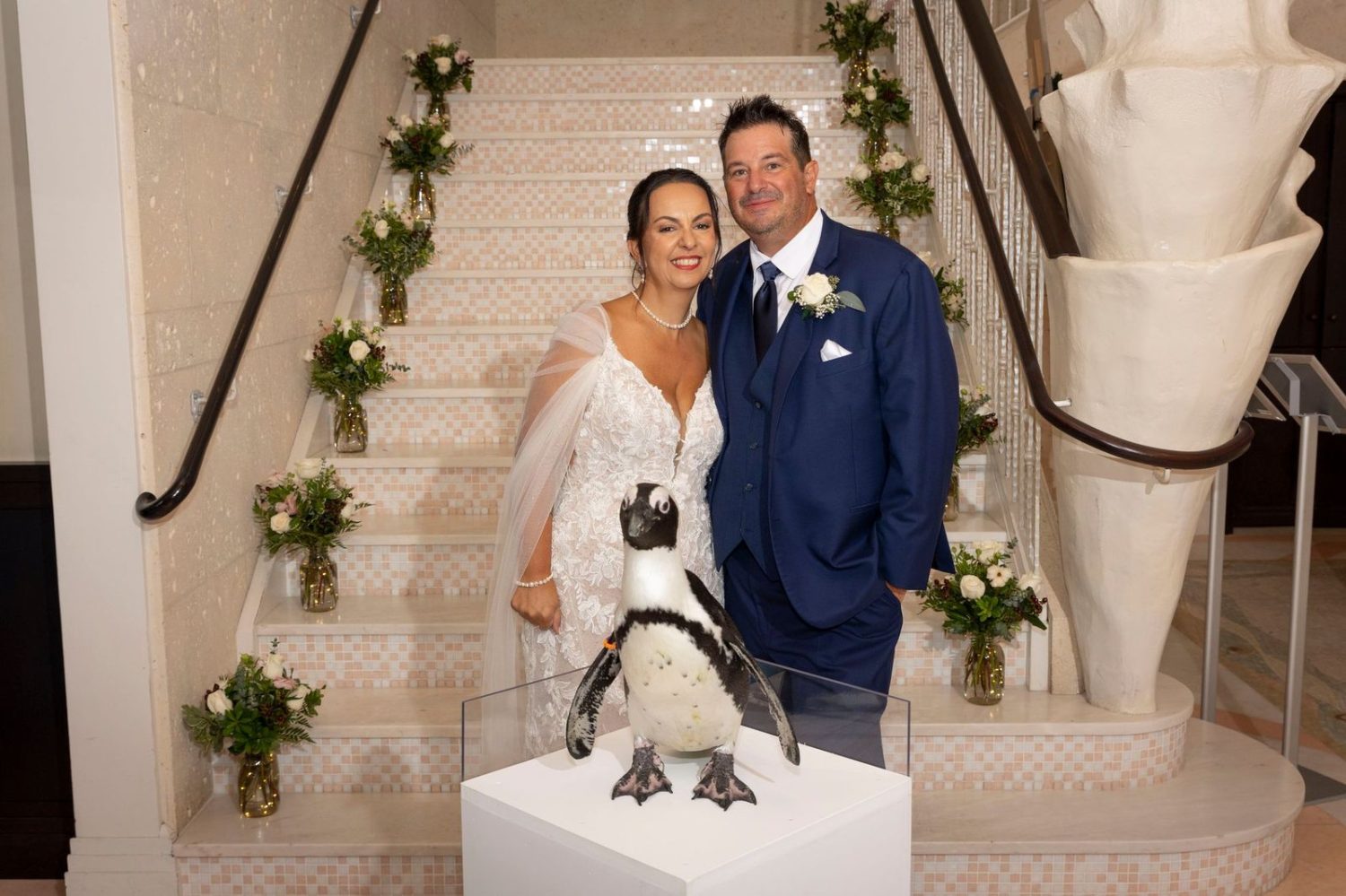 Bride and groom with penguin in front of stairs