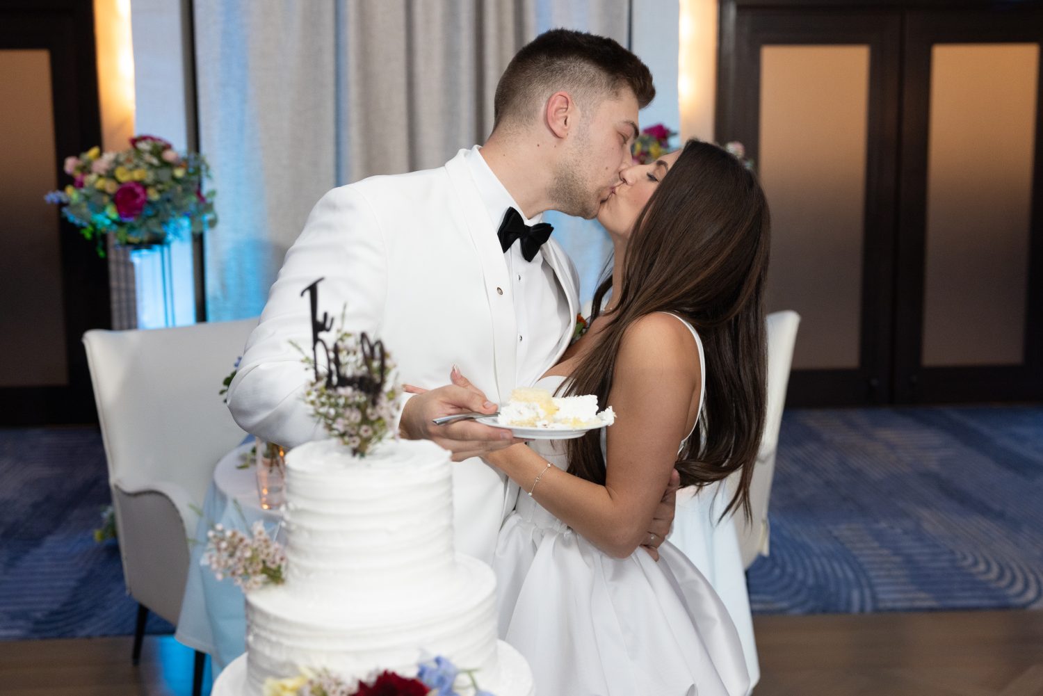 Bride and Groom kiss in front of wedding cake