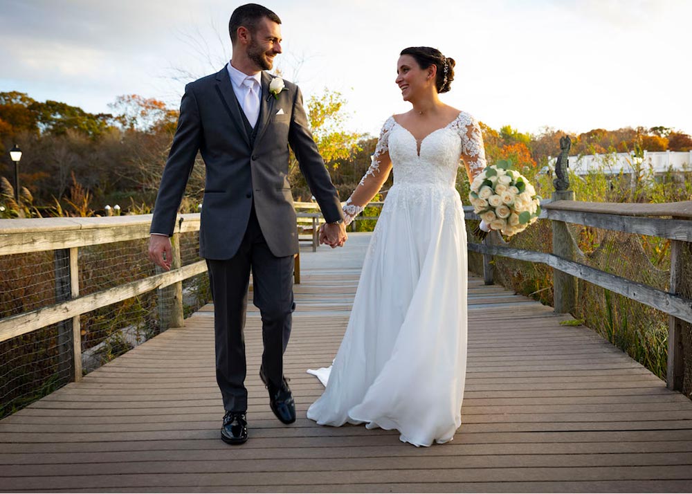 Bride and groom walking along the waterfront boardwalk in autumn